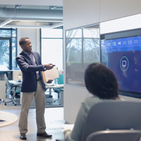 A man presenting information on a screen to a seated person
